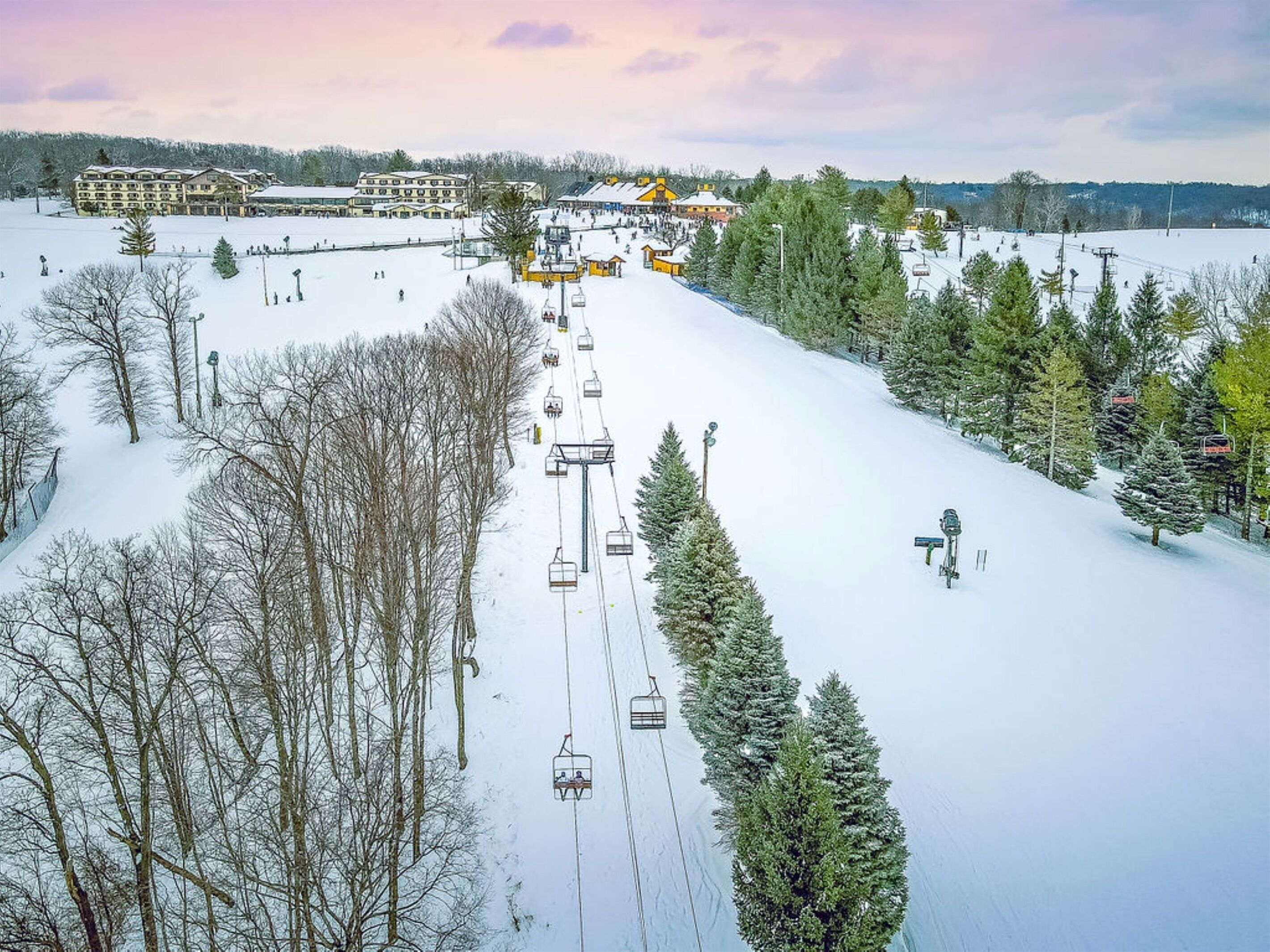 A ski resort with a chairlift, snow-covered slopes, and buildings in the background.