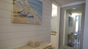 Ein Badezimmer mit einem Holzbadezimmerschrank, einem großen Spiegel und einem Gemälde eines Segelbootes an der Wand.