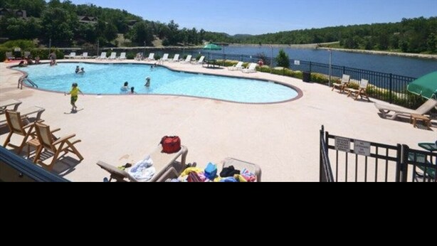 A swimming pool with lounge chairs and a view of a lake. - Branson, Stone Bridge Resort Studio (Reeds Spring)