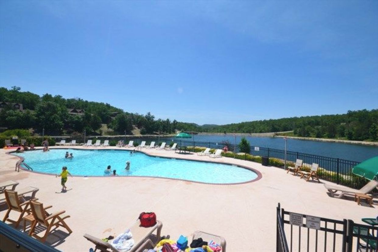 A swimming pool with lounge chairs and a view of a lake.