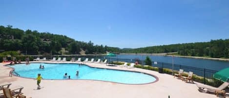 A swimming pool with lounge chairs and a view of a lake.
