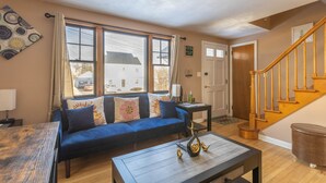 A living room with a blue sofa, a wooden coffee table, and a staircase. - Luxury Home Central to Farmington, Plainville & Downtown New Britain (New Britain)