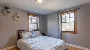 A bedroom with a bed, two windows, a ceiling light, and wall-mounted shelves. - Luxury Home Central to Farmington, Plainville & Downtown New Britain (New Britain)