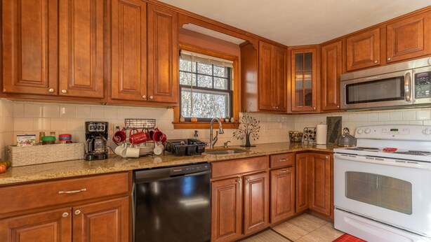 A kitchen with wooden cabinets, a dishwasher, a stove, and a microwave. - Luxury Home Central to Farmington, Plainville & Downtown New Britain (New Britain)