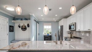 A modern kitchen with white cabinets, a marble countertop, and pendant lighting. - Class A Condo - located in Belleair Beach, FL (Belleair Beach)