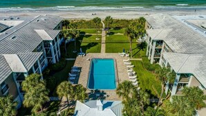 A hotel with a swimming pool surrounded by palm trees and a beach view. - Class A Condo - located in Belleair Beach, FL (Belleair Beach)