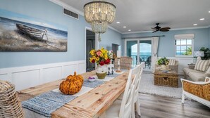 A dining area with a wooden table, a chandelier, and a painting of a boat on the wall. - Class A Condo - located in Belleair Beach, FL (Belleair Beach)