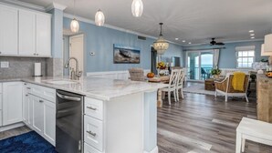 A spacious kitchen with white cabinets, a marble countertop, and pendant lighting. - Class A Condo - located in Belleair Beach, FL (Belleair Beach)