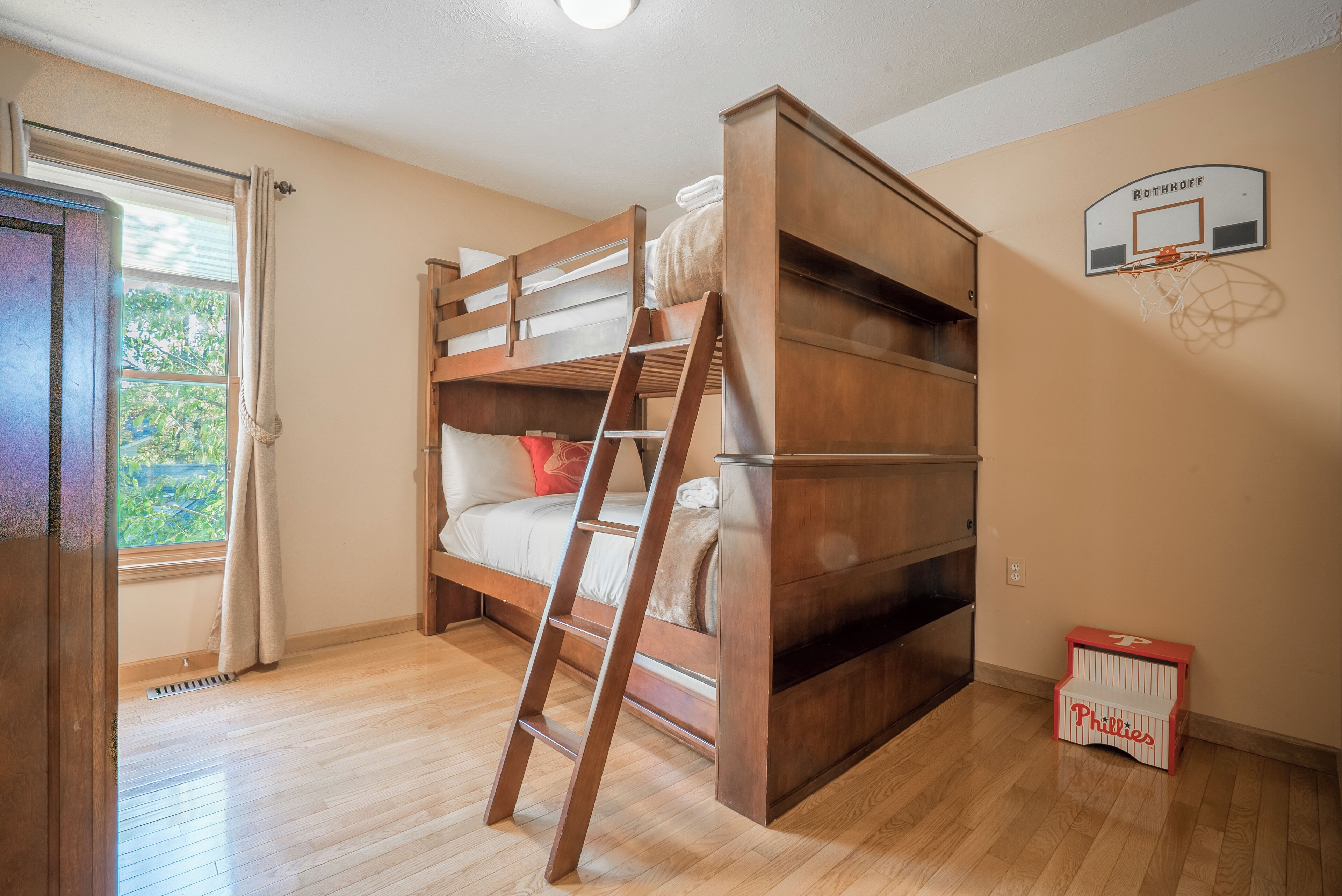 Habitación con literas, un aro de baloncesto y una ventana con cortinas.