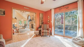 Un salón amplio con un espejo grande, chimenea y vistas al exterior a través de un ventanal corredero.