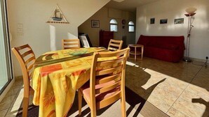 Een zithoek met een tafel, stoelen, een rode bank en een vloerlamp.
