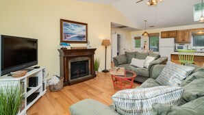 A living room with a fireplace, a television, and a sofa. - Family Entertainment Beach House, Hot tub, Nature Park, Fire pit, Pizza Oven (Emerald Isle)