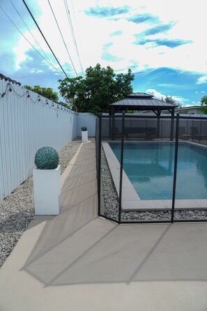 A backyard with a swimming pool, a covered seating area, and a white fence. - ☀️🏝😎 MIAMI PARADISE - 11 people 🛌 (Miami)