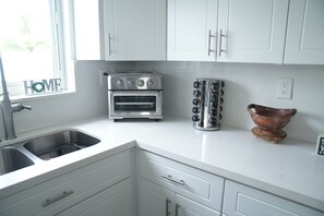 A kitchen with white cabinets, a built-in oven, a toaster, and a sink.