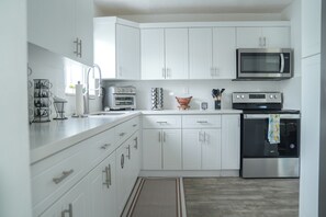 A modern kitchen with white cabinets, stainless steel appliances, and a built-in microwave.