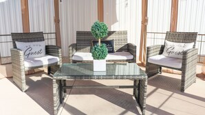 A patio area with wicker furniture, a glass table, and a small potted plant.