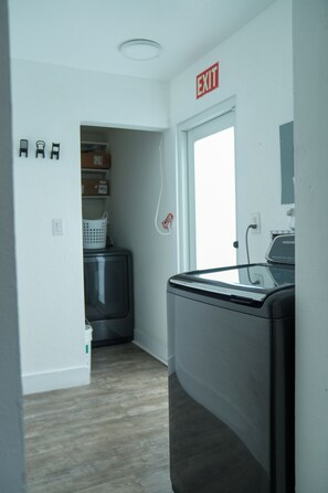 A laundry room with a washing machine, a dryer, and an exit sign.