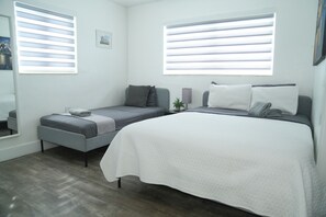 A bedroom with a single bed, a small sofa, and a bedside table.
