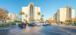 A parking lot with multiple vehicles, surrounded by tall buildings and palm trees. - NEW - Spacious Studio close to Theme Parks (Orlando)
