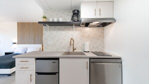 A compact kitchen with a modern design, featuring a built-in dishwasher, a coffee maker, and a microwave. - NEW - Spacious Studio close to Theme Parks (Orlando)