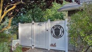 A white wooden gate with a circular emblem and a welcome sign for Acorn Cottage.