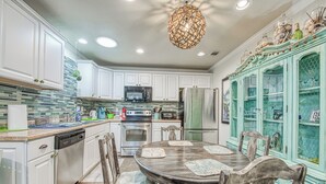 A kitchen with white cabinets, a central island, and a dining area with a round table and chairs.