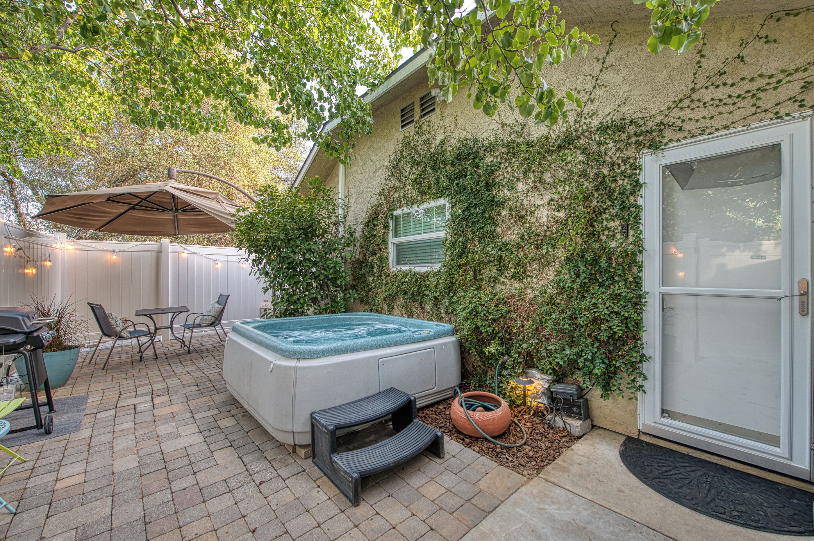 A backyard patio with a hot tub, outdoor furniture, and a covered seating area.