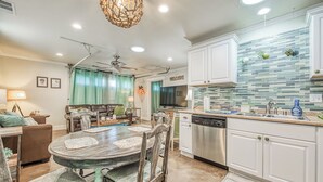 A modern kitchen with white cabinets, a dishwasher, and a tiled backsplash.
