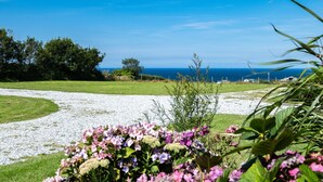A gravel path leading to a grassy area with a view of the sea and trees. - Harbour Lodge (Port Isaac)