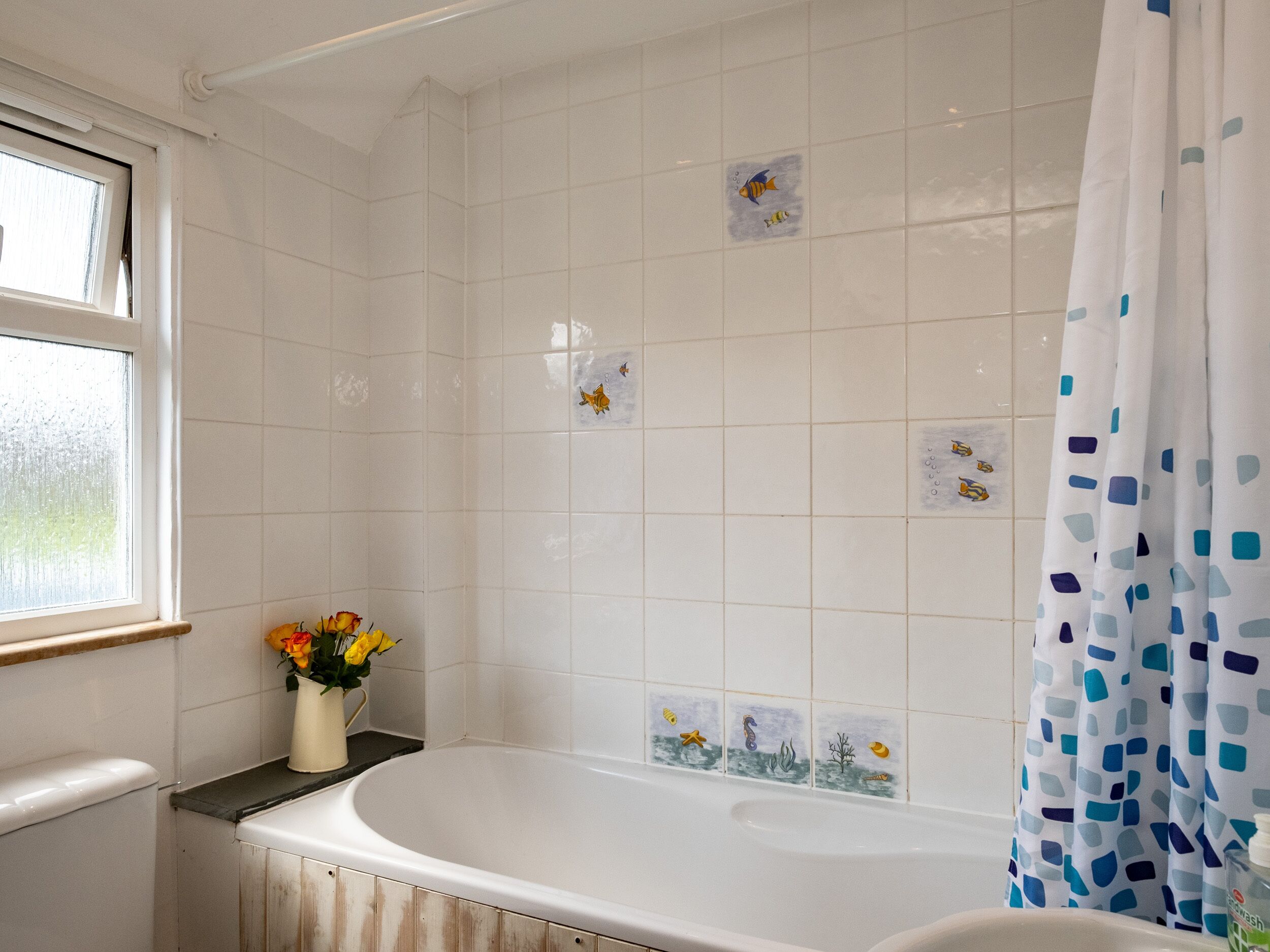 A bathroom with a bathtub, a window, and a shower curtain.