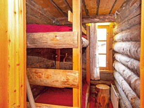 Ein Blockhaus-Interieur mit Etagenbetten, einer Holztür und einem Fenster.