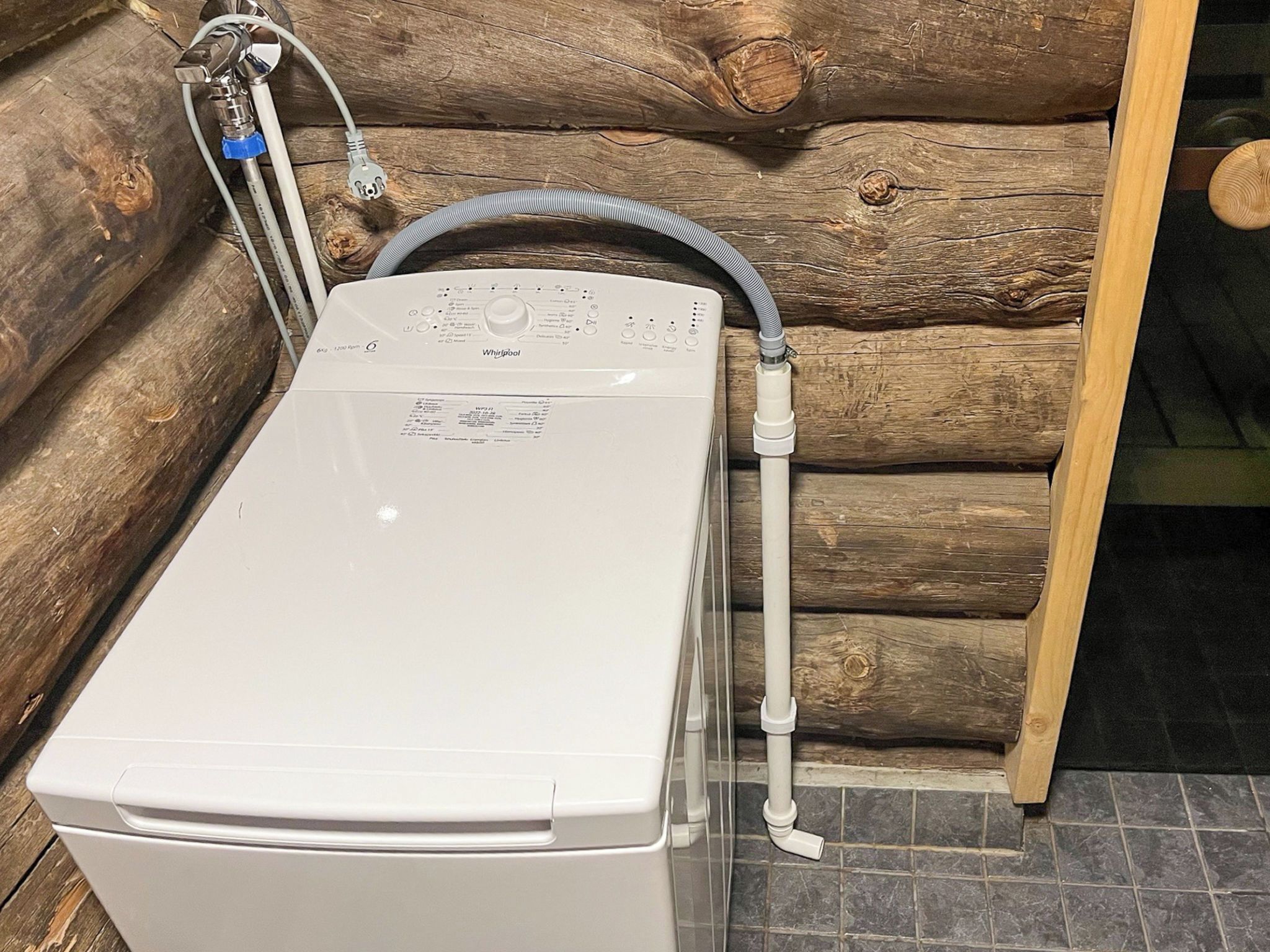 A front-loading washing machine in a log cabin setting.