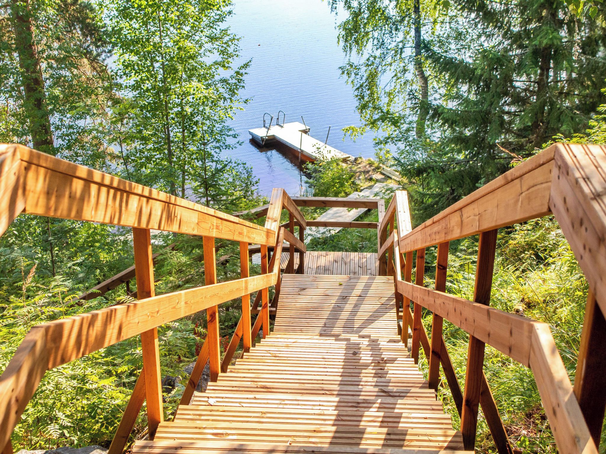 A wooden boardwalk leading to a dock over water, surrounded by trees.
