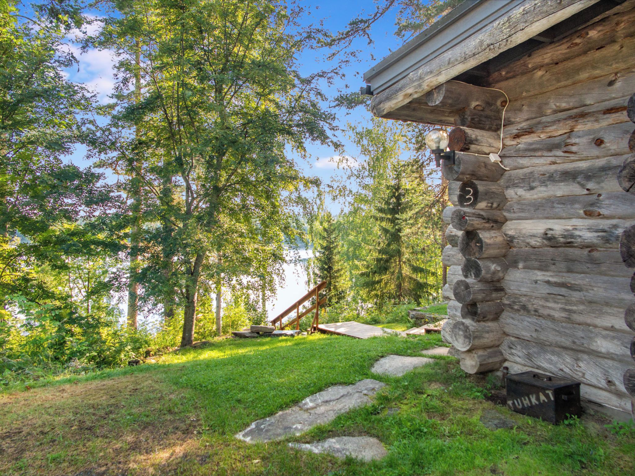 A log cabin with a stone staircase leading to a wooden deck.