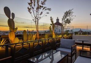 A rooftop terrace with a glass table, seating area, and cacti. - Hotel Tamara (Puebla)