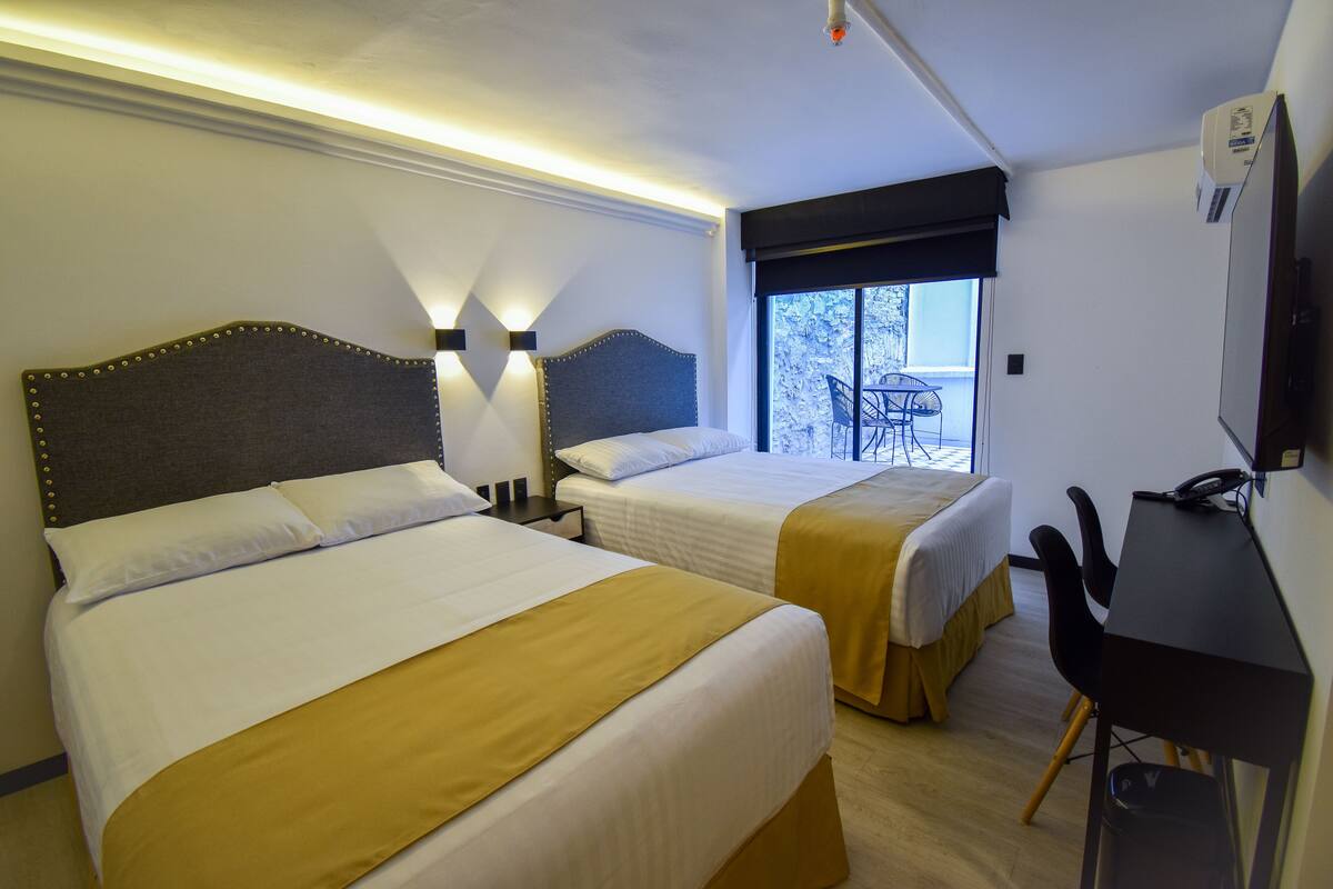 Habitación de hotel con dos camas, un escritorio y una silla.