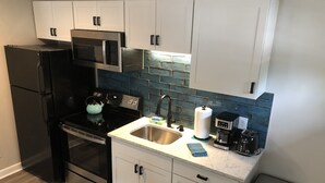 Una cocina moderna con armarios blancos, un refrigerador negro, electrodomésticos de acero inoxidable y un salpicadero azul.