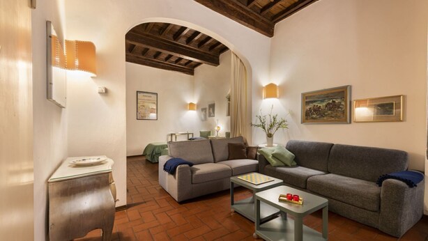 A living room with a sofa, armchair, coffee table, and a small side table. - Pitti Studio apartment by Mmega (Firenze)