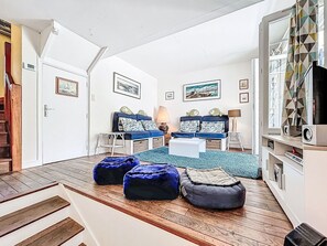 Ein gemütliches Wohnzimmer mit einer Couch, Hocker, einem Couchtisch und einem Fernseher.