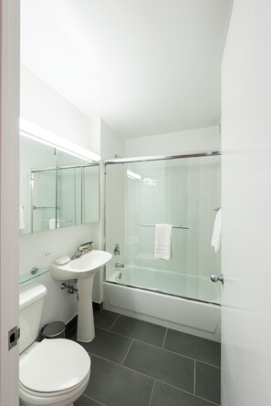 Ein modernes Badezimmer mit einer Duschkabine aus Glas, einem weißen Waschbecken und einer Toilette.