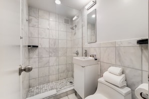 A modern bathroom with a shower, toilet, and sink.