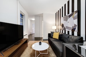 A modern living room with a flat-screen TV, a coffee table, a sofa, and a painting on the wall.