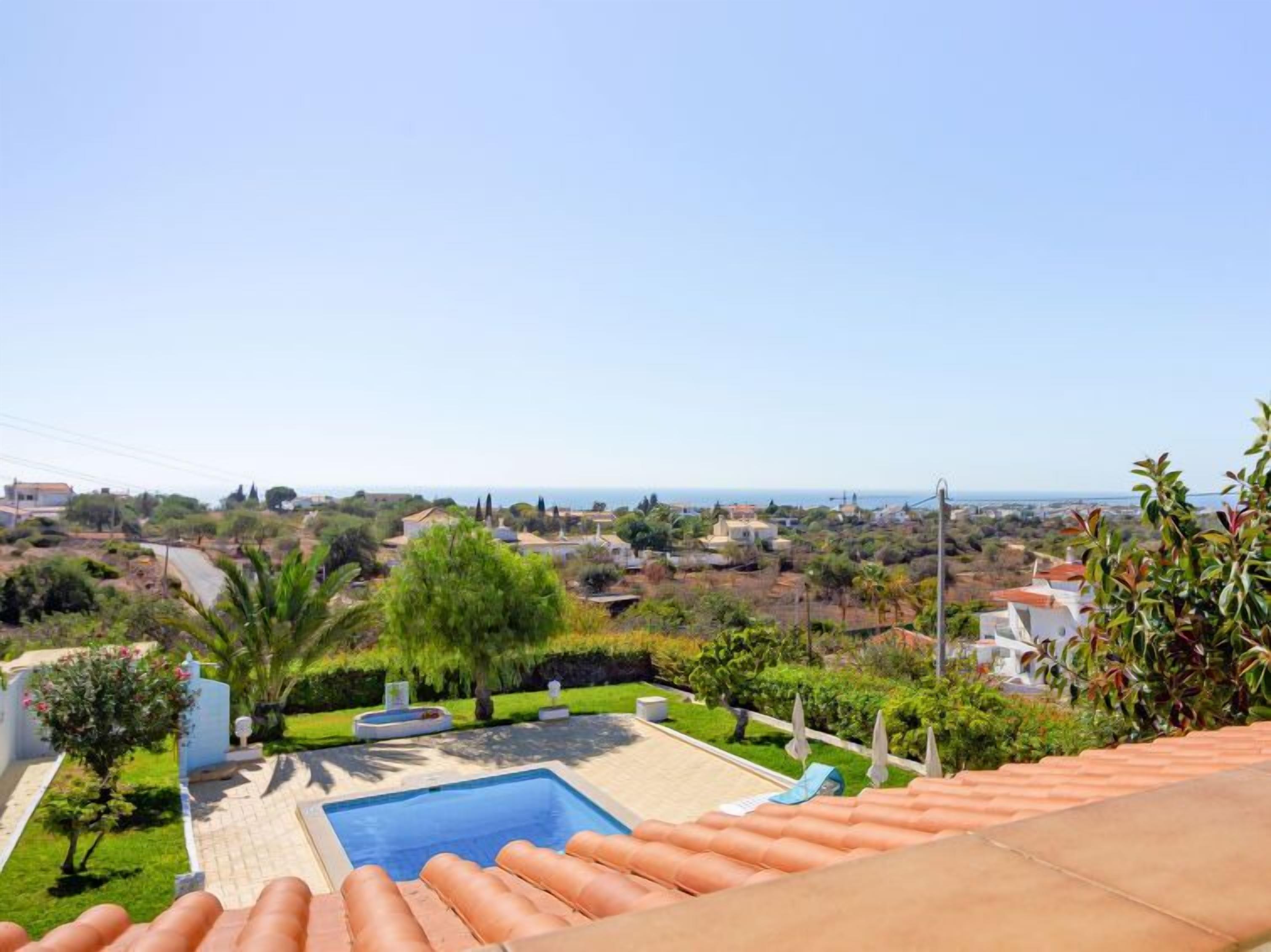 A pool area with a view of the surrounding landscape and distant buildings.