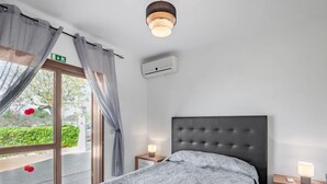 A bedroom with a bed, bedside tables, a ceiling light, and a window with curtains.