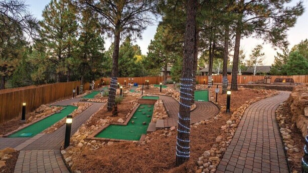 A miniature golf course with multiple lanes, wooden fences, and trees.