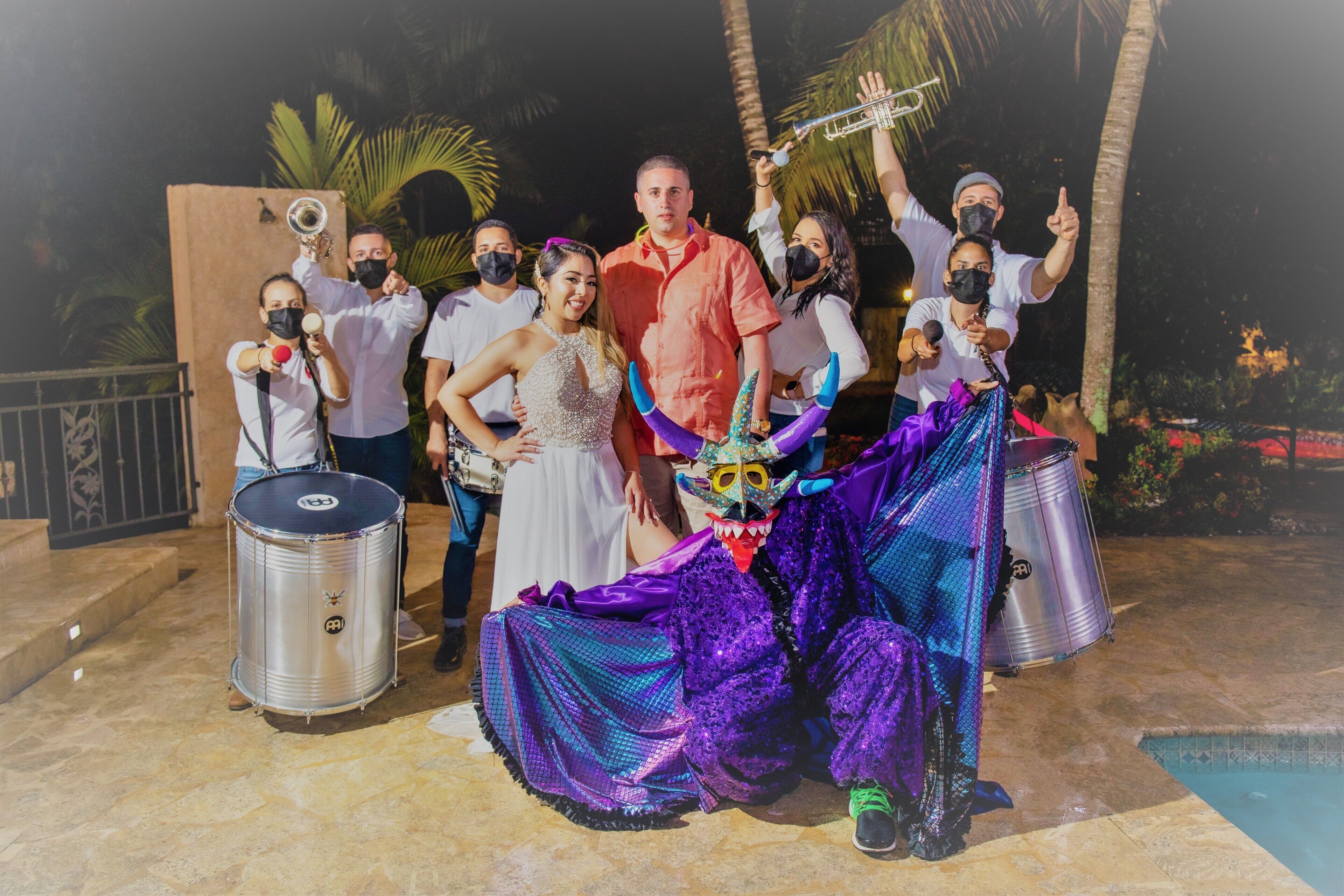 A group of people in a festive setting with musical instruments and a decorative mask.
