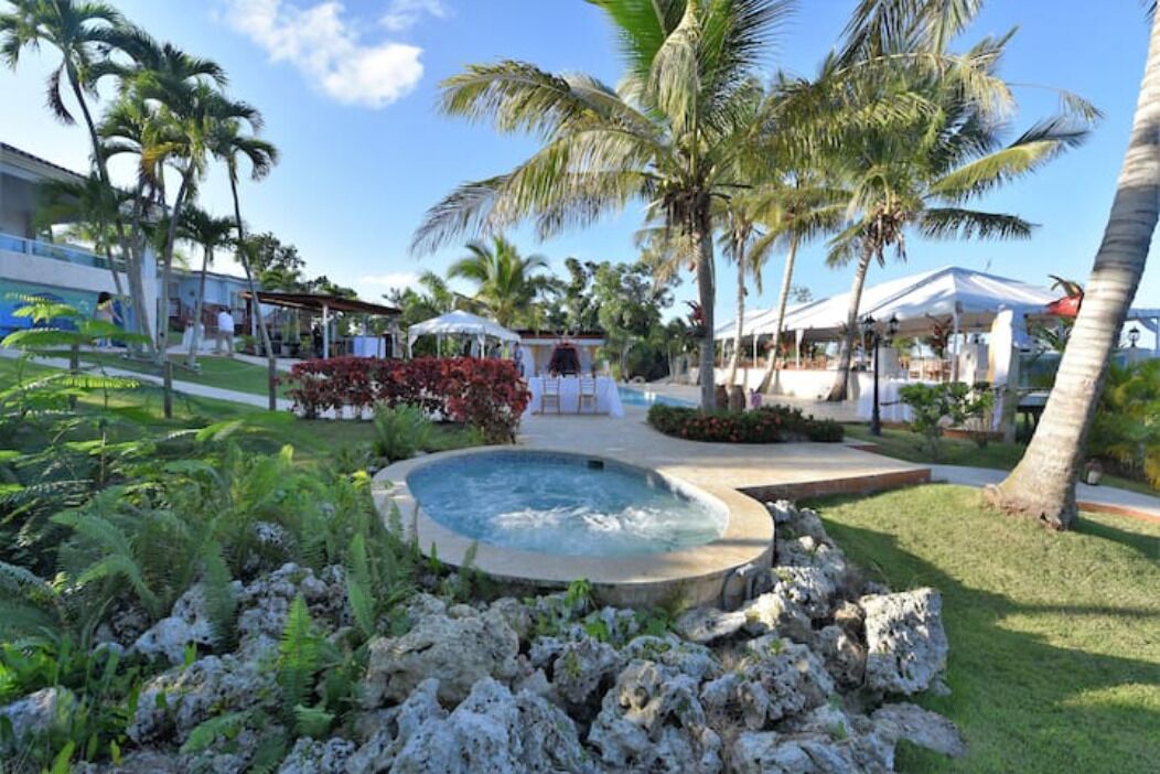 A pool area with palm trees, a hot tub, and a covered seating area.