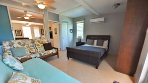 Une chambre à coucher comprenant un lit, un canapé, une table de chevet et un ventilateur de plafond.
