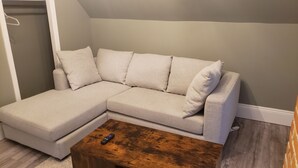 A L-shaped sectional sofa with five cushions, a wooden coffee table, and a gray wall. - Rosé All Day King Studio | Retro Vibes | Downtown| (Fredericton)