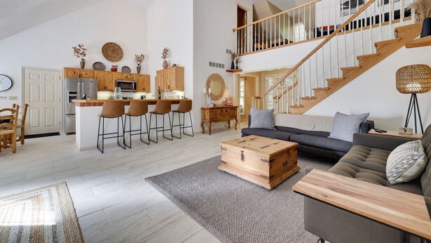 Een ruime woonkamer met een bank, salontafel en een trap naar een verdieping erboven.